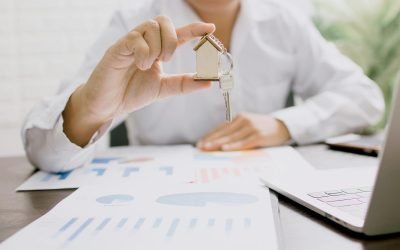 Professionnel de l'immobilier présentant une maquette de maison avec clés, symbolisant l'investissement immobilier et la propriété.