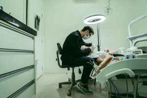 Un dentiste portant un masque soigne un patient dans une clinique dentaire moderne.
