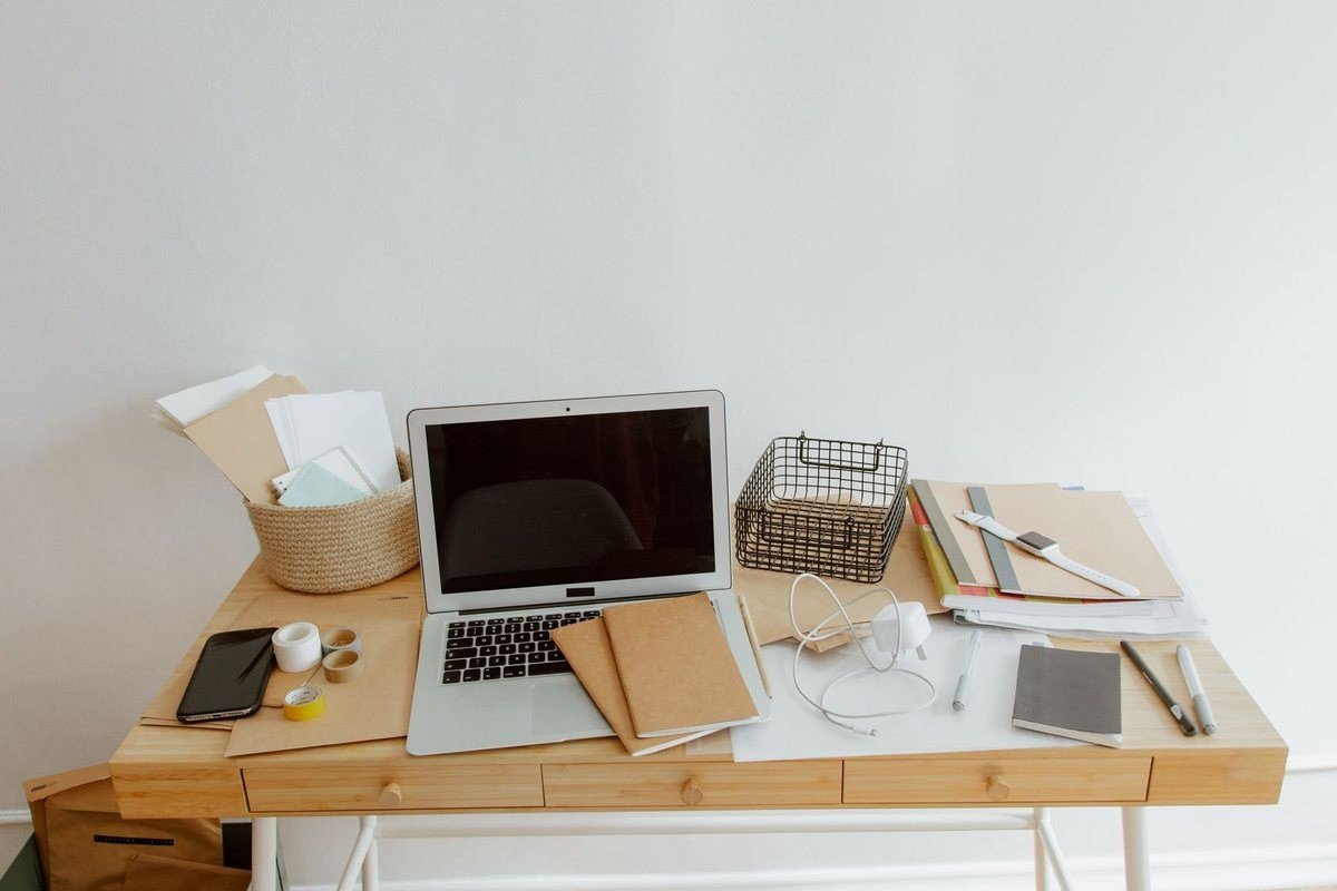 Bureau blanc avec ordinateur portable, documents, téléphone et fournitures disposés organisés