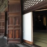 Portes en bois ouvertes sur un sol tatami, décorations rouges suspendues