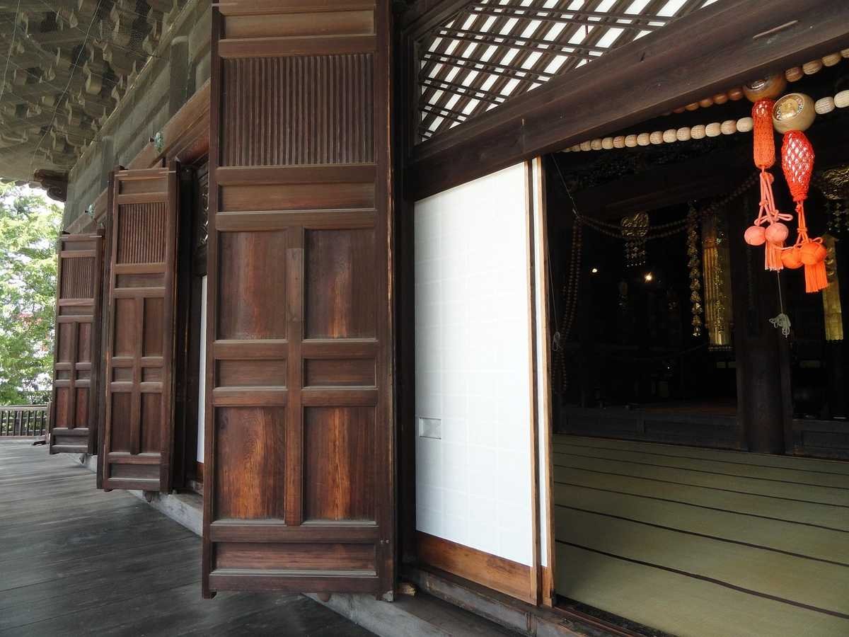 Portes en bois ouvertes sur un sol tatami, décorations rouges suspendues