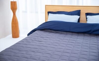 Un lit avec draps bleus, oreillers, lampe en bois et fenêtre