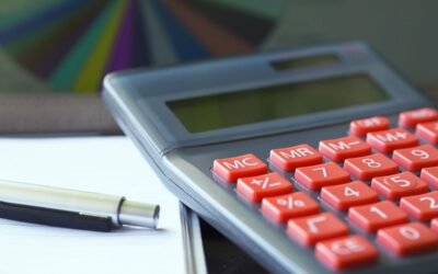 Calculatrice avec boutons rouges, stylo et feuille sur une table