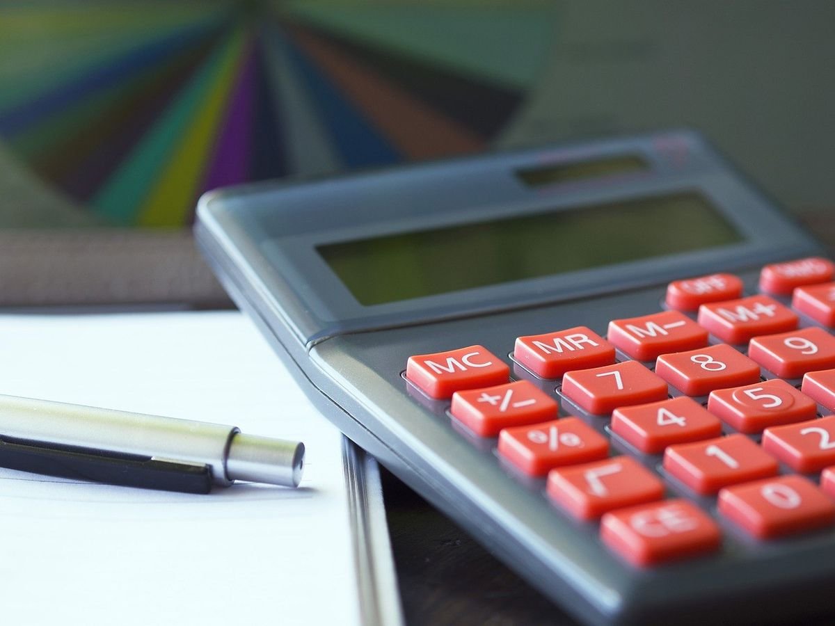 Calculatrice avec boutons rouges, stylo et feuille sur une table