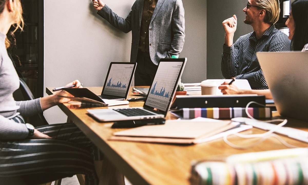 Groupe de professionnels en réunion autour d'une table avec tablettes et ordinateurs portables