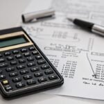 Calculatrice, stylos et documents financiers avec tableaux de chiffres sur un bureau
