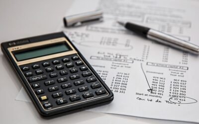 Calculatrice, stylos et documents financiers avec tableaux de chiffres sur un bureau
