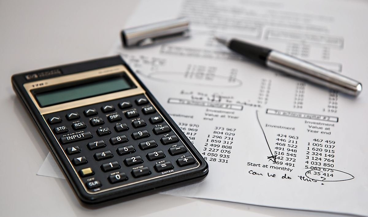 Calculatrice, stylos et documents financiers avec tableaux de chiffres sur un bureau