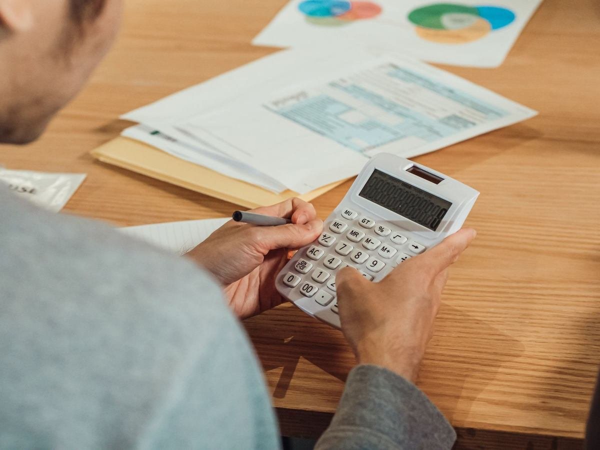 Homme utilisant une calculatrice et un stylo sur un bureau avec des documents
