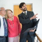 Homme en costume pointant un document, deux personnes observant, dans un bureau